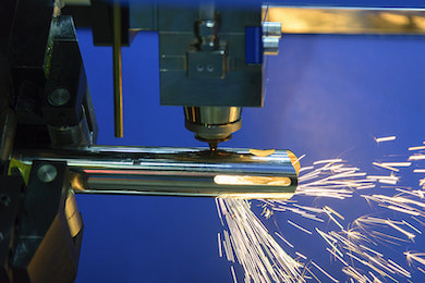 Laser cutting machine cutting a medical part with sparks flying